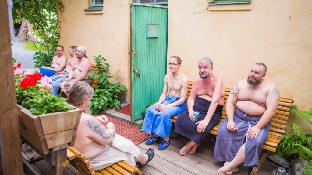 Bastubadare med handdukar runt midjan svalkar sig utomhus