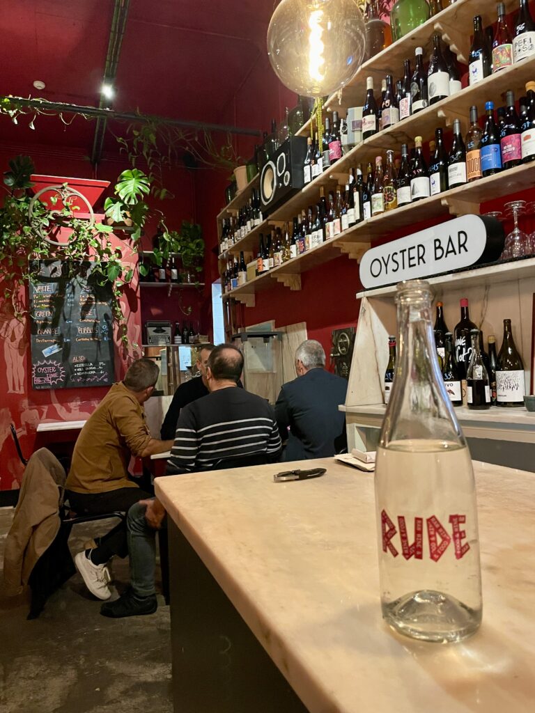 En restaurang med ett vitt bord, en flaska med texten "Rude". 