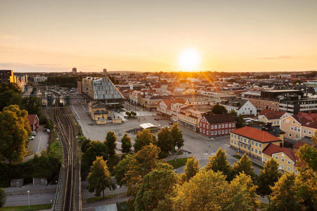 Flygvy över Växjö, statsmiljö i solnedgång, tågspår går tvärs över bilden. 