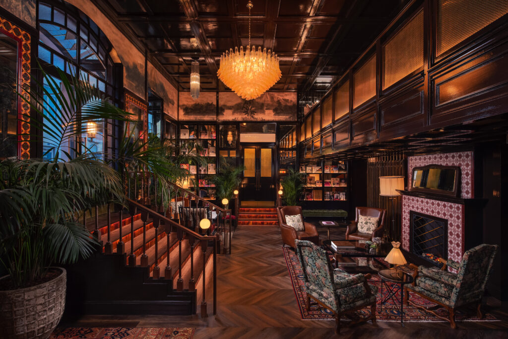 En mörk och rikt ornamenterad hotellobby med orientalisk touch, en trappa från vänster, blommiga fåtöljer. 