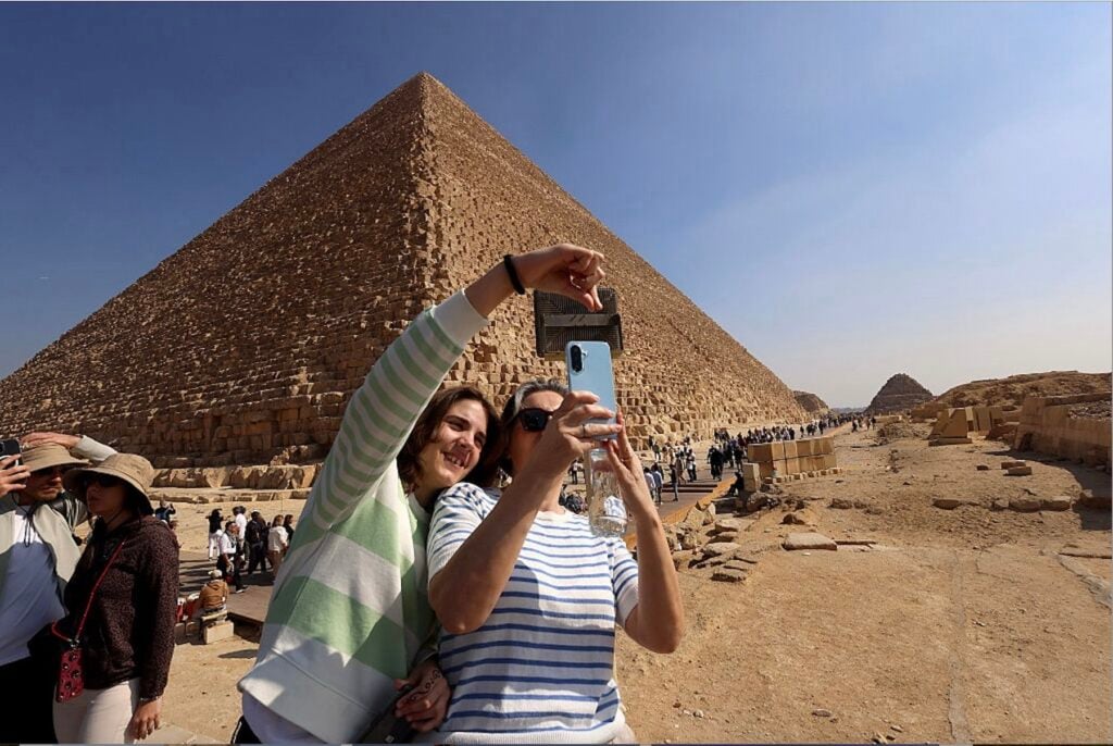 Egyptens pyramider och två turister som tar selfies.