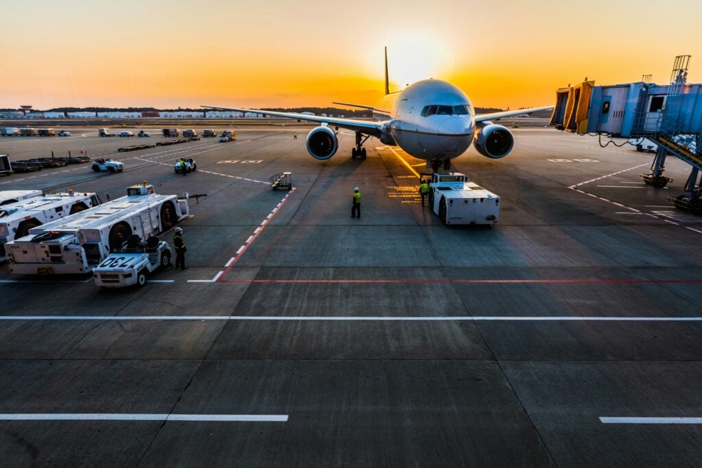 Ett flygplan i solnedgången utanför en terminal på en flygplats.