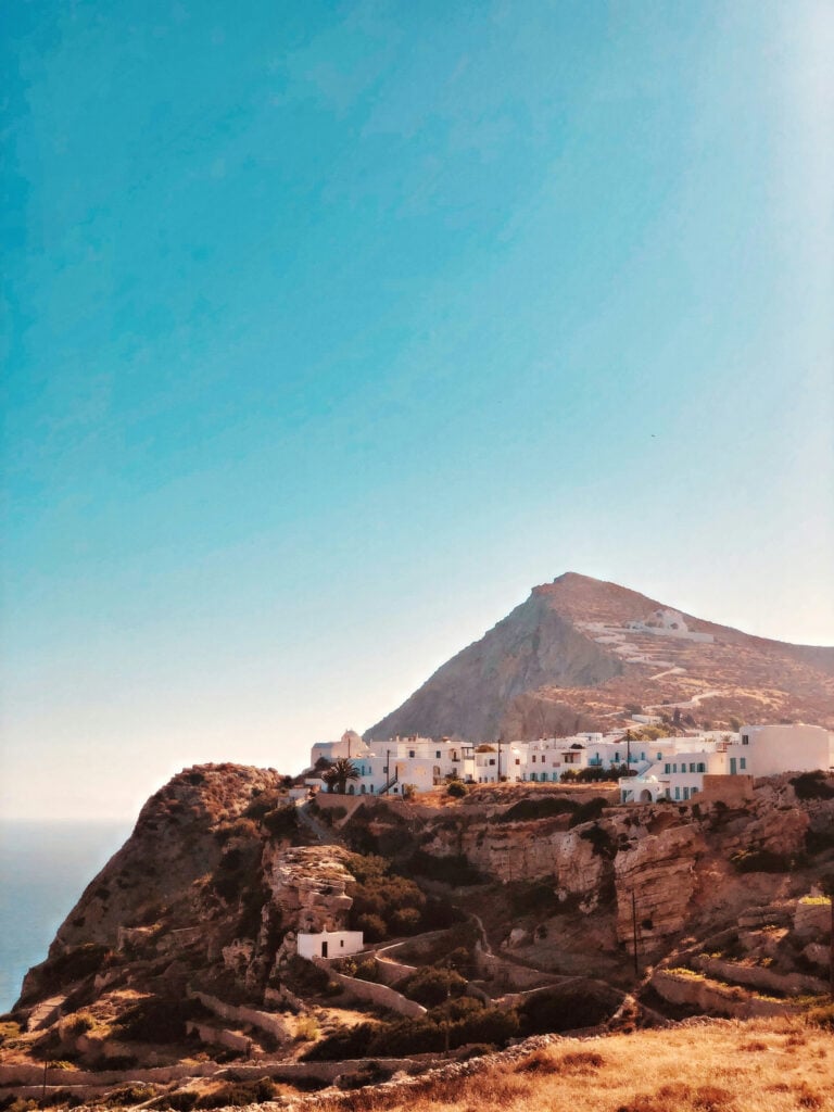 Små vita hus balanserar på en stor brun bergssida, syns från långt håll. 