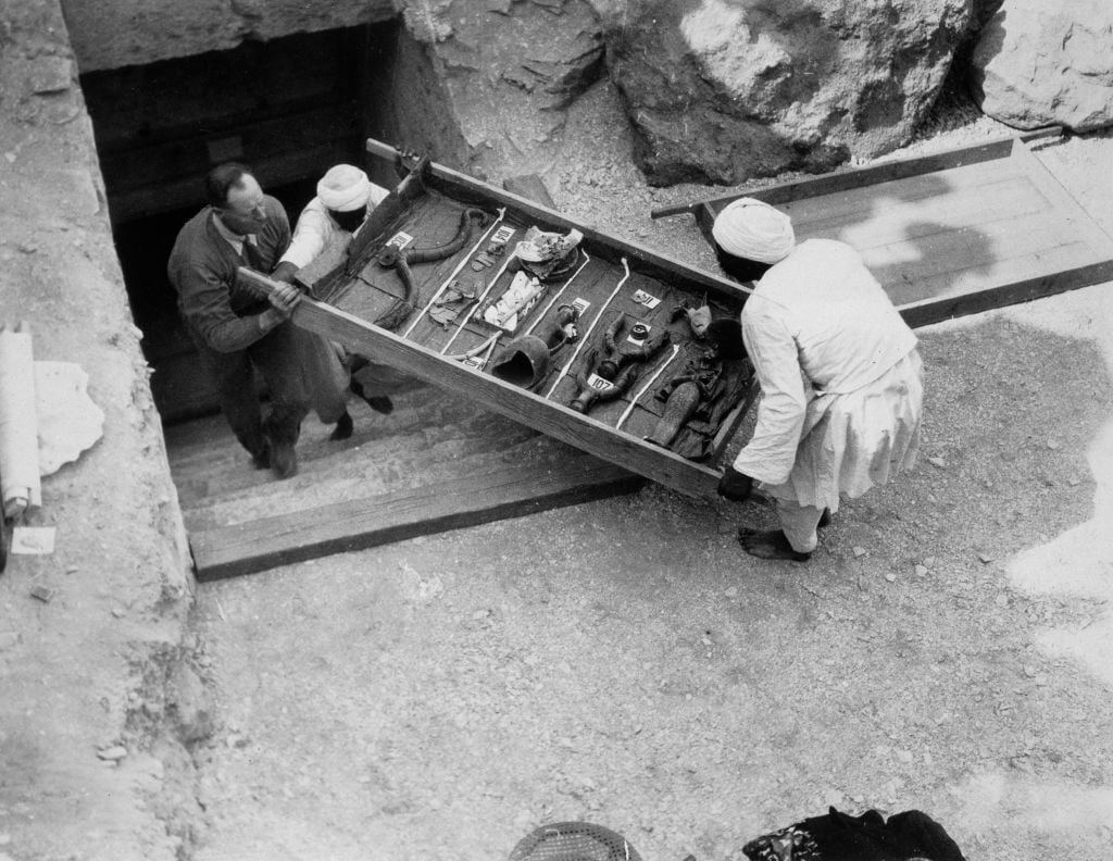 En arkeolog och en egyptisk bärare bär upp fynd ur Tutankhamons grav 1922.