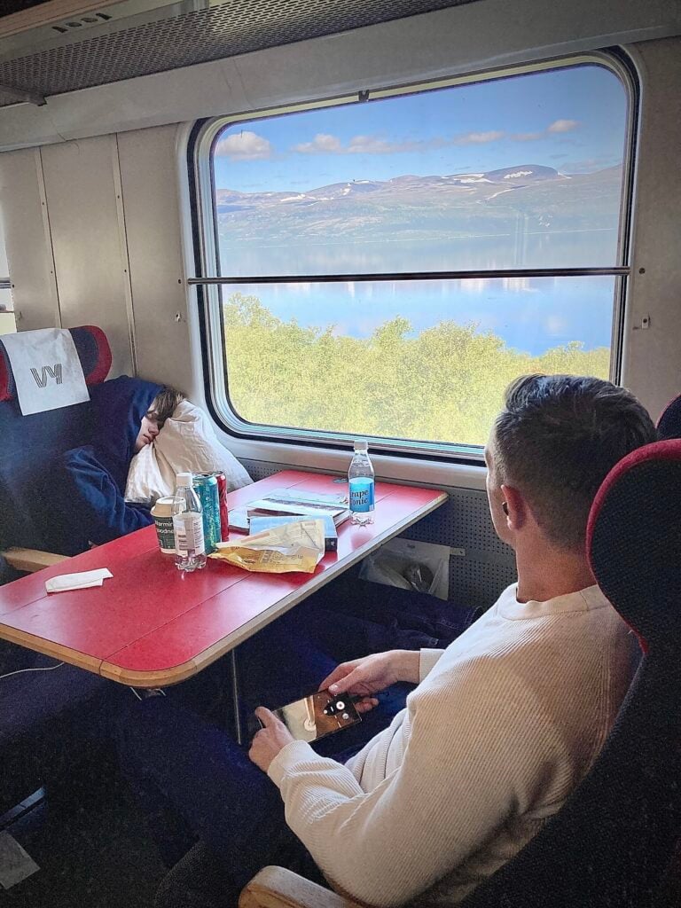 Två resenäer på tåg med fjäll utanför fönstret.