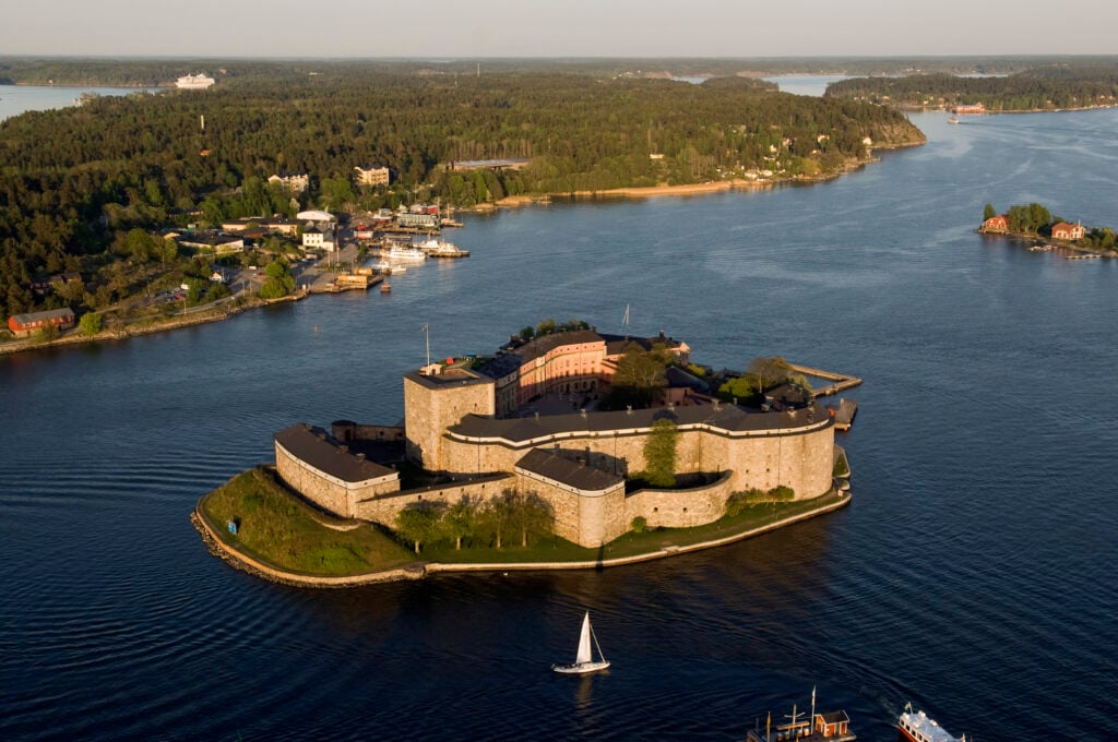 Aerial view of castle on island, hav och båtar runtom.