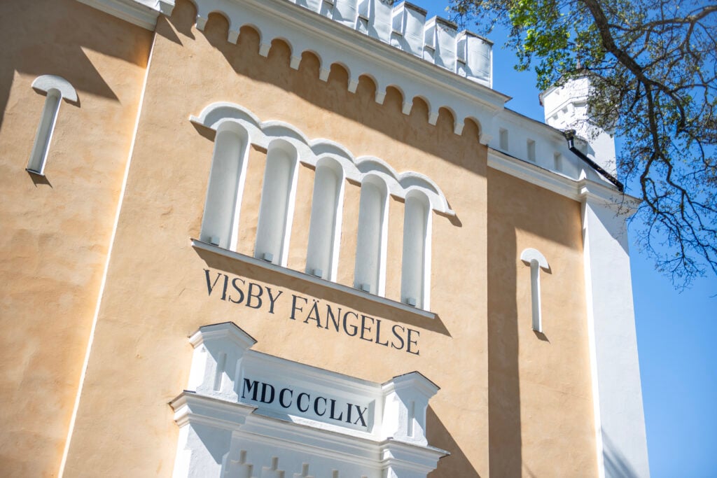 En beige husfasad med vita fönsterbågar.