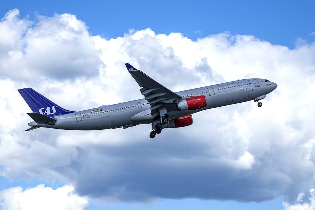 Airbus-plan från SAS flyger med vita moln i bakgrunden.