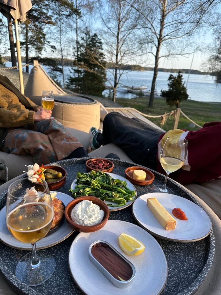 Ett litet bord med många små tallrikar på en altan, havet framför. 