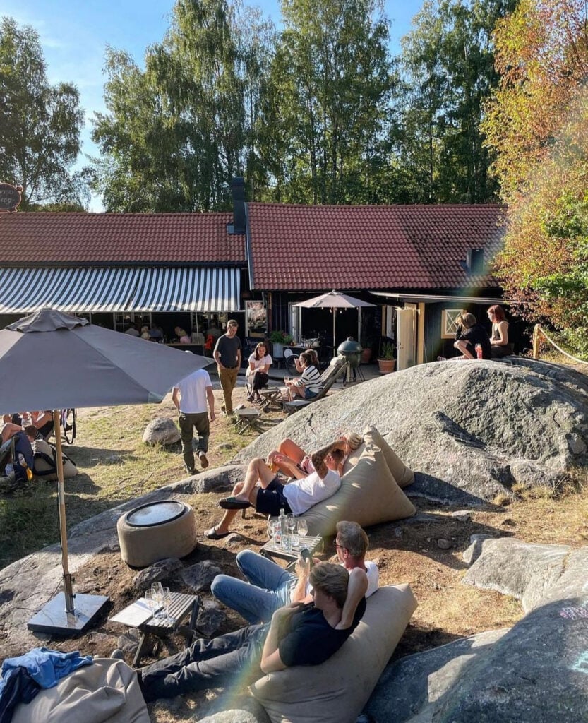 Människor sitter bland klippor bredvid ett restauranghus. 