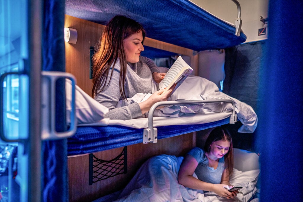 Två personer ligger i varsin tågsäng och läser mellan lakanen.