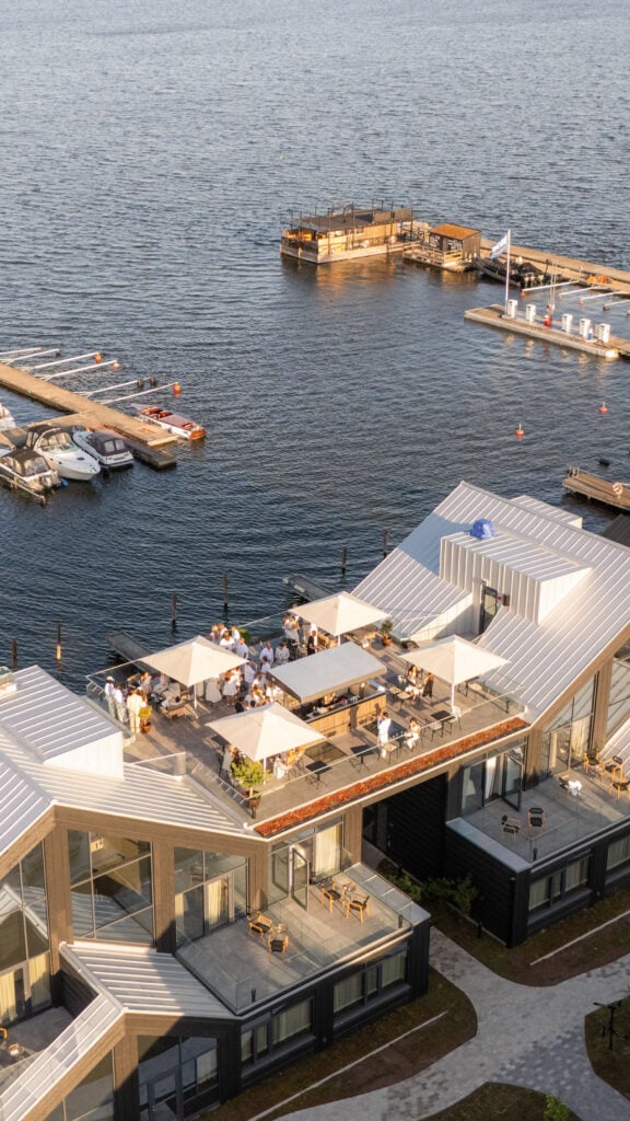 En drönarvy över hotellet med ett soldäck på taket, framför havet.