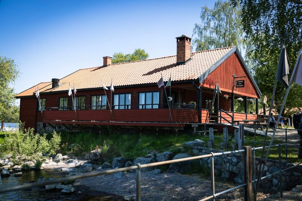 Rött hus omgivet av gröna träd.