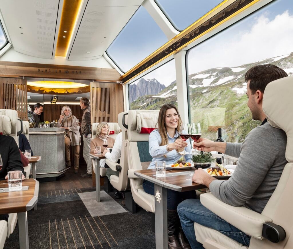 Resenärer i vacker lyxig tågvagn som åker mellan höga berg