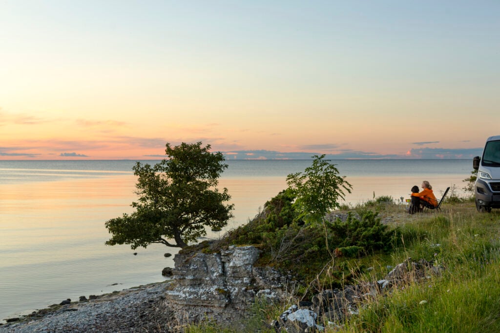 Ett par tittar på utsikten i solnedgången ovanför havet på en kalkstensklippa.