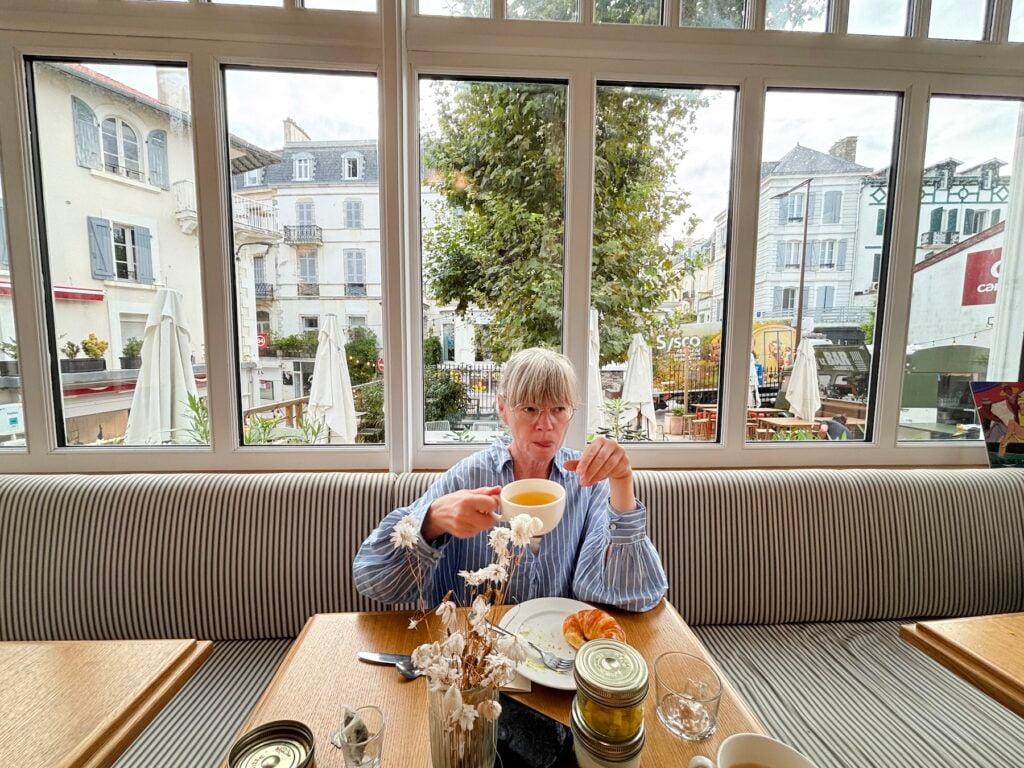 Kvinna i frukostmatsal dricker kaffe och äter frukost.