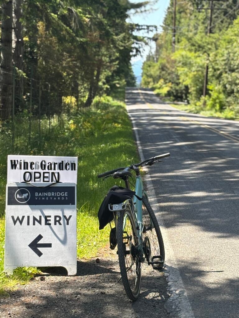 Cykel parkerad vid väg och skylt som gör reklam för vinprovning.