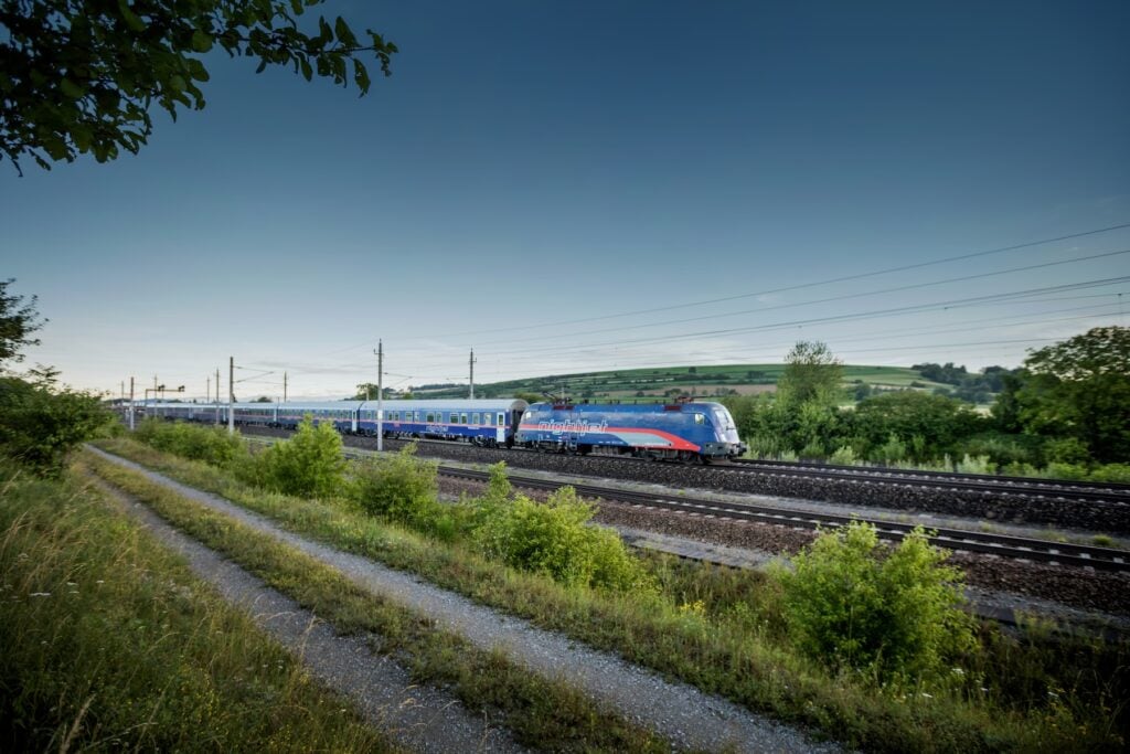 Blått tåg som kör över platt landskap