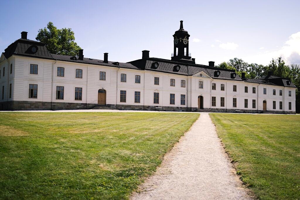 Vitt rokokoslott med svart tak och gångstig som leder upp till det.