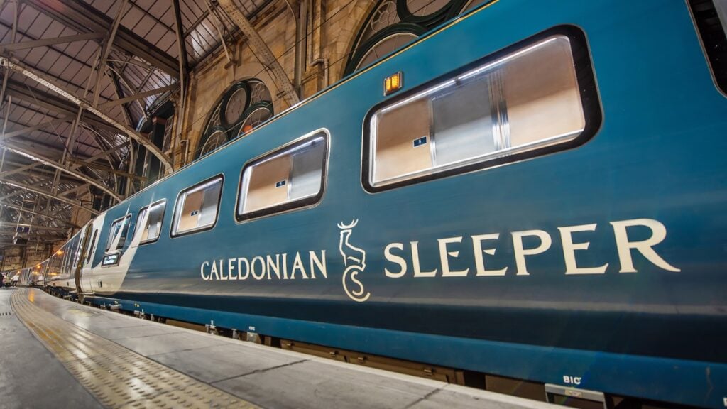 Blått tåg vid perrong. På tåget står det Caledonian Sleeper.