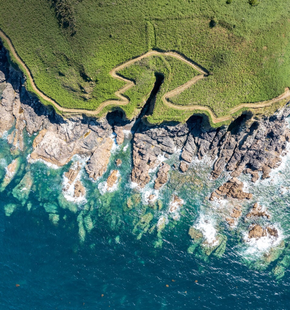 Kuststig längs Bretagnes klippor med utsikt över havet och en undangömd badvik.