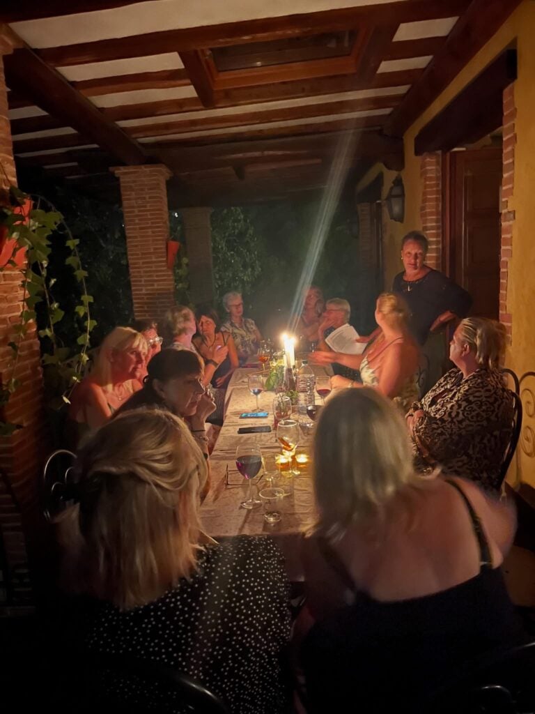 En grupp människor sitter i mörkret vid ett dukat bord med levande ljus.
