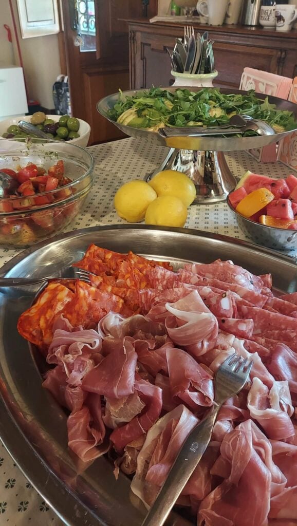 En tallrik med chark på ett dukat bord med sallader och frukter.