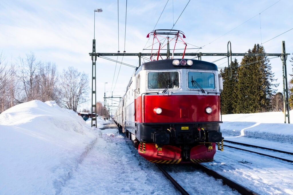 Grått och rött rc-lok i vinterlandskap.