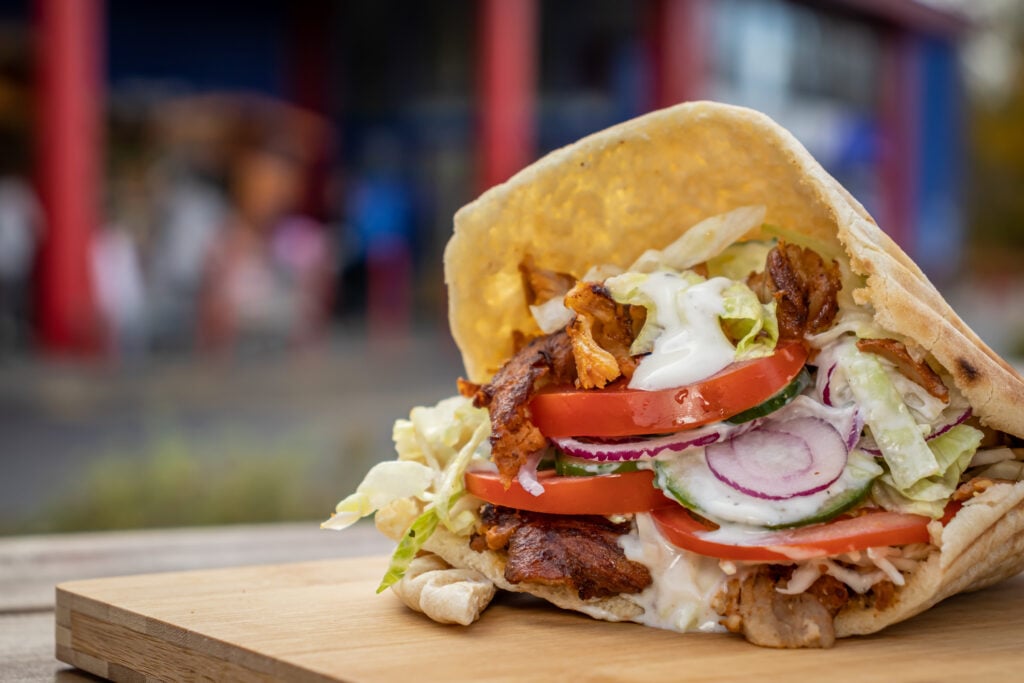 Döner kebab i pitabröd på en bricka utomhus.