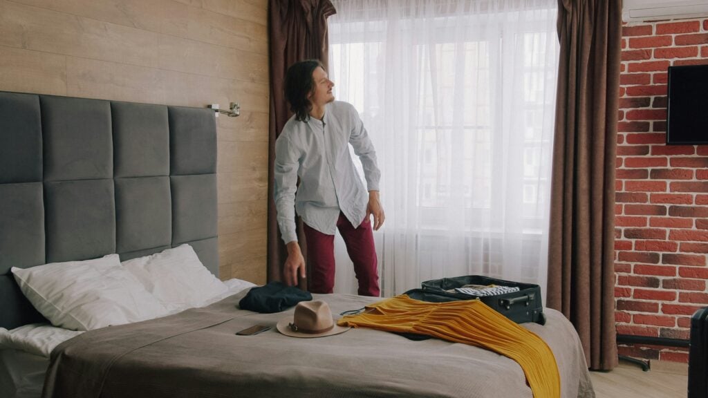 En man packar upp kläder på ett hotellrum. 